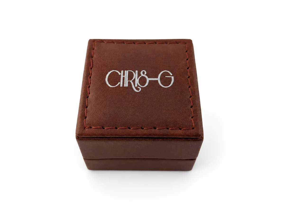 Kompakte braune Schmuckbox mit hellem Chris-G.-Logo auf dem Deckel