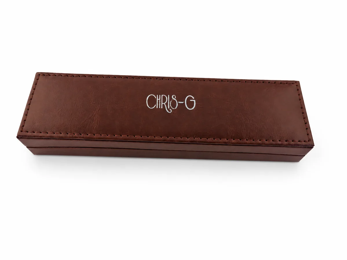 Längliche braune Schmuckbox mit Chris-G.-Logo und umlaufender Naht